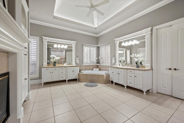 bathroom with tile patterned floors, vanity, ceiling fan, crown molding, and a relaxing tiled tub