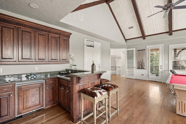 kitchen featuring sink, dark wood-type flooring, high vaulted ceiling, kitchen peninsula, and pool table