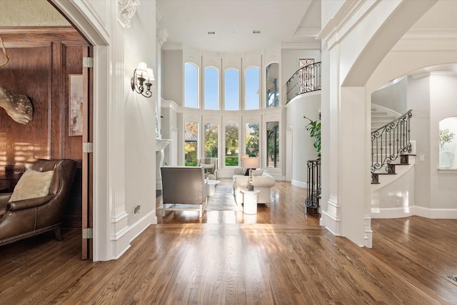 entrance foyer featuring crown molding, hardwood / wood-style floors, and a towering ceiling