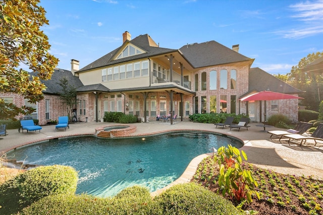 rear view of house featuring a patio and a pool with hot tub