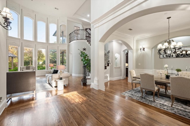 interior space featuring a notable chandelier, wood-type flooring, ornamental molding, and a high ceiling