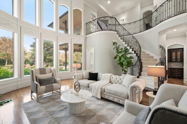 living room featuring a towering ceiling, ornamental molding, and hardwood / wood-style flooring