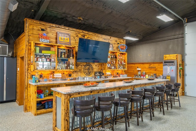 bar featuring light carpet, vaulted ceiling, and wood walls