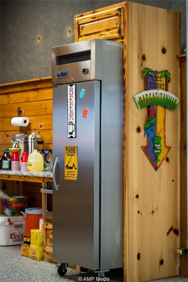 kitchen with stainless steel refrigerator and wood walls