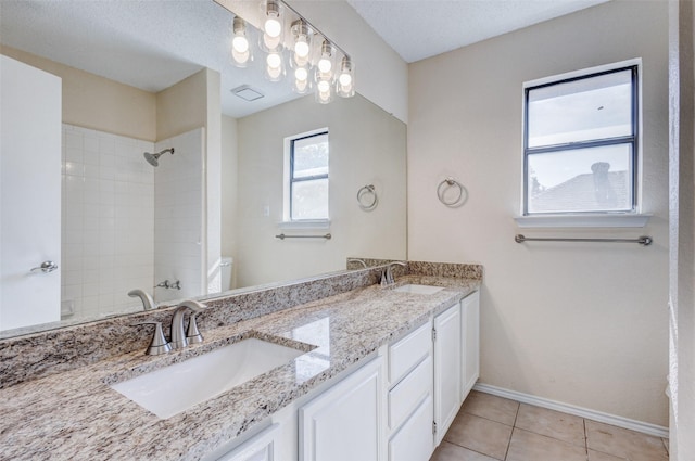 bathroom featuring tile patterned flooring, vanity, a tile shower, a textured ceiling, and toilet