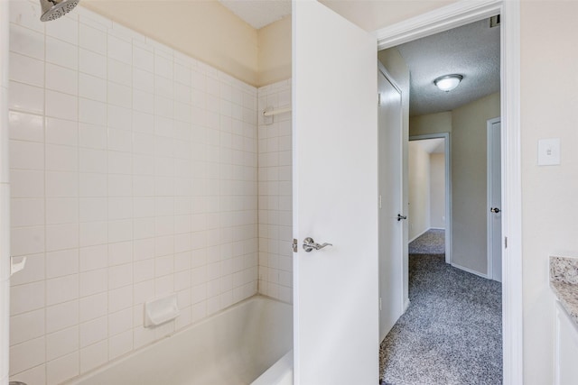 bathroom featuring tiled shower / bath, vanity, and a textured ceiling