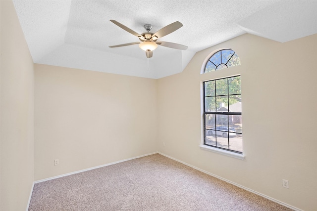 empty room featuring lofted ceiling, ceiling fan, carpet floors, and a textured ceiling