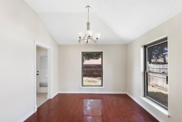 unfurnished dining area with dark wood-type flooring, vaulted ceiling, a textured ceiling, and a chandelier