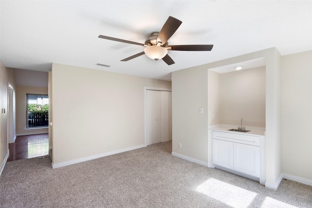 interior space featuring ceiling fan, light colored carpet, a closet, and indoor wet bar