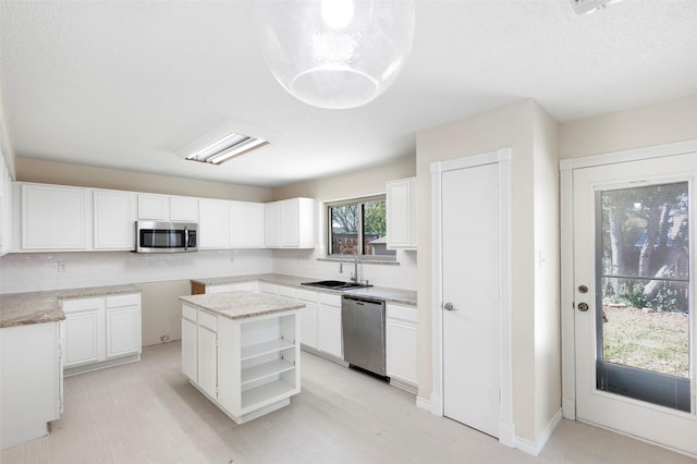 kitchen featuring stainless steel appliances, white cabinetry, a center island, and sink