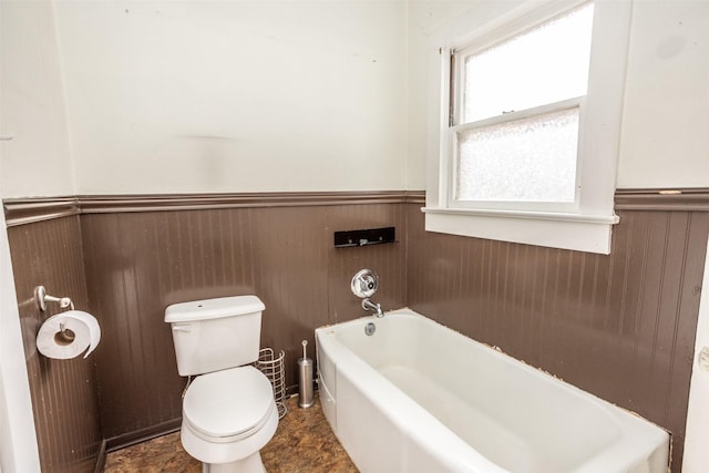 bathroom with wooden walls, a tub to relax in, and toilet