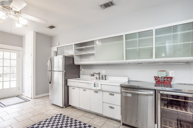 kitchen with ceiling fan, beverage cooler, white cabinets, light tile patterned flooring, and appliances with stainless steel finishes