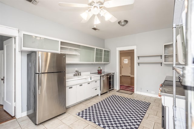 kitchen with appliances with stainless steel finishes, light tile patterned floors, white cabinets, and ceiling fan