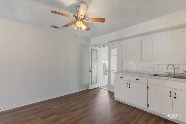 kitchen with backsplash, white cabinetry, sink, and a textured ceiling