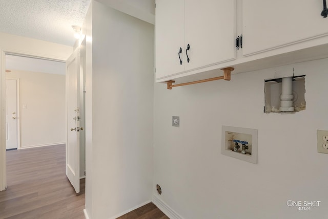 laundry room with electric dryer hookup, cabinets, hookup for a washing machine, light wood-type flooring, and a textured ceiling