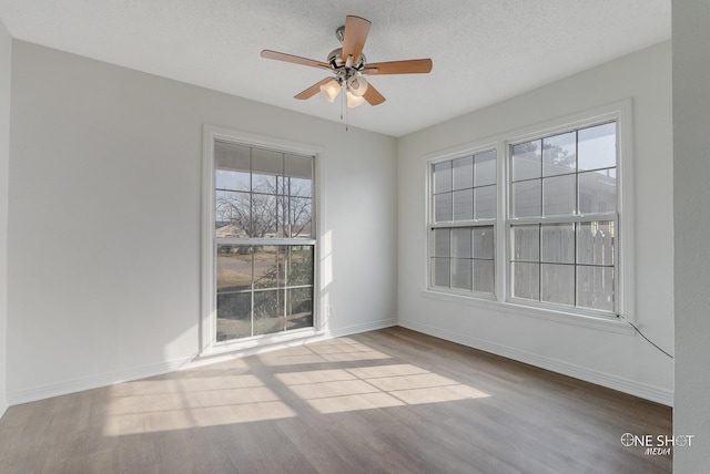 empty room with ceiling fan, wood-type flooring, and a textured ceiling