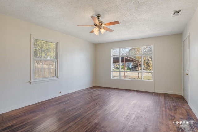 spare room with plenty of natural light, dark wood-type flooring, a textured ceiling, and ceiling fan