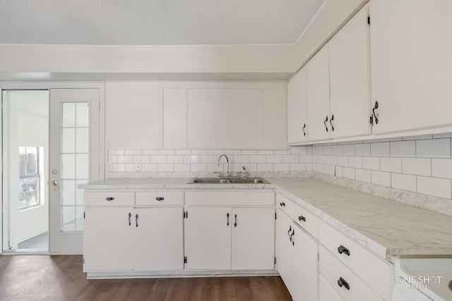 kitchen with backsplash, white cabinetry, sink, and a textured ceiling