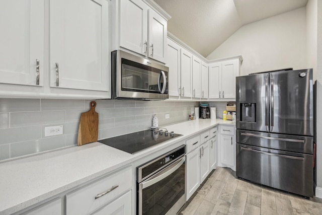 kitchen featuring white cabinets, light hardwood / wood-style floors, lofted ceiling, and appliances with stainless steel finishes