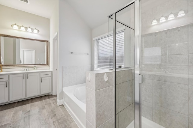 bathroom featuring hardwood / wood-style floors, vanity, shower with separate bathtub, and vaulted ceiling