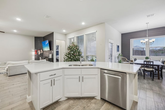 kitchen with stainless steel dishwasher, a kitchen island with sink, sink, white cabinets, and hanging light fixtures