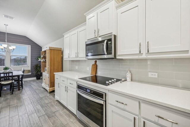 kitchen with white cabinetry, appliances with stainless steel finishes, an inviting chandelier, and decorative backsplash