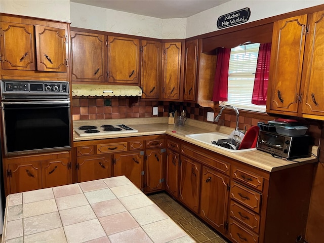 kitchen with tile counters, sink, white gas stovetop, oven, and decorative backsplash