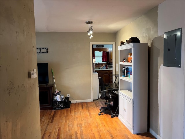 home office featuring electric panel, light hardwood / wood-style flooring, and washer / clothes dryer