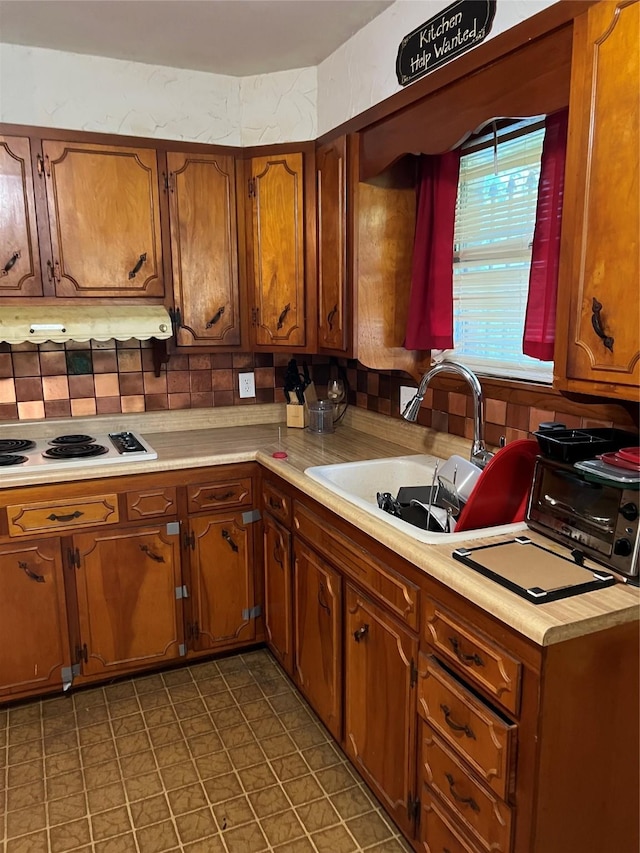 1019 W Bullock St, Denison, TX 75020 - kitchen featuring white electric stovetop, light countertops, under cabinet range hood, and a sink