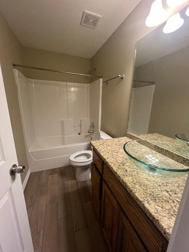 full bathroom with bathing tub / shower combination, hardwood / wood-style floors, vanity, and toilet