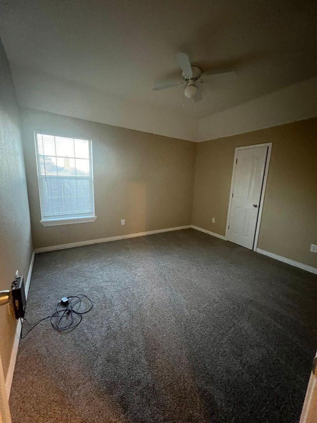 spare room featuring ceiling fan and dark colored carpet