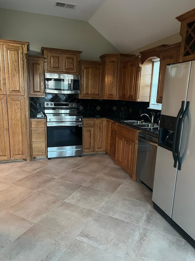 kitchen featuring decorative backsplash, sink, appliances with stainless steel finishes, and vaulted ceiling