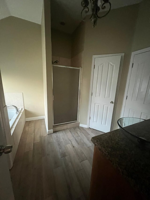 bathroom featuring hardwood / wood-style flooring, separate shower and tub, and lofted ceiling