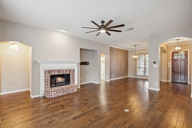 unfurnished living room with dark hardwood / wood-style floors, crown molding, a fireplace, and ceiling fan with notable chandelier