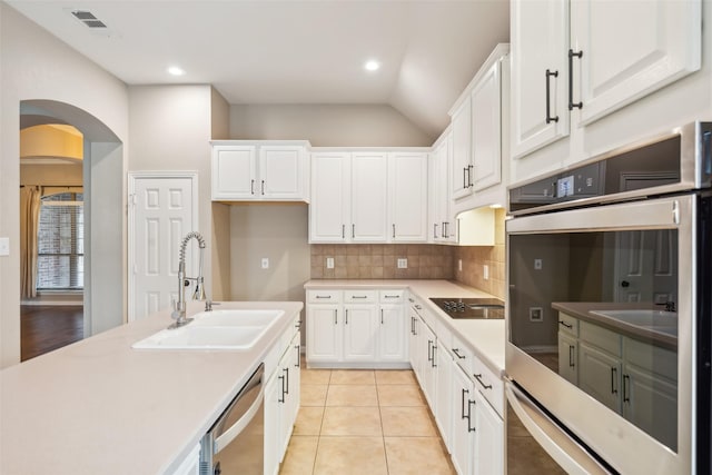 kitchen with vaulted ceiling, sink, light tile patterned floors, dishwasher, and white cabinets