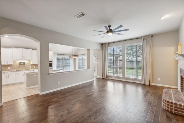 unfurnished living room featuring ceiling fan, light hardwood / wood-style floors, and a brick fireplace