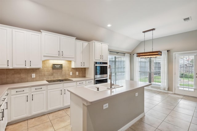 kitchen with white cabinetry, an island with sink, and vaulted ceiling