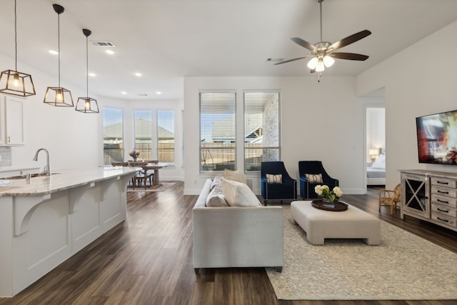 living room with ceiling fan, dark hardwood / wood-style floors, and sink