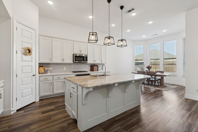 kitchen with sink, an island with sink, white cabinets, and appliances with stainless steel finishes