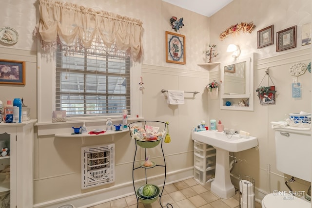 bathroom featuring heating unit, tile patterned floors, and toilet