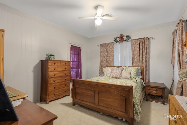 bedroom featuring light colored carpet, ceiling fan, and wood walls