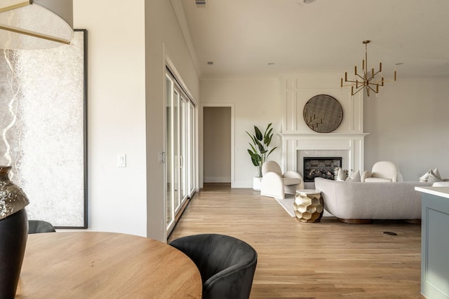 living room with an inviting chandelier, a wealth of natural light, a large fireplace, and light wood-type flooring