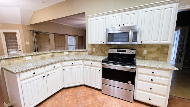 kitchen with white cabinets, appliances with stainless steel finishes, tasteful backsplash, and light stone countertops