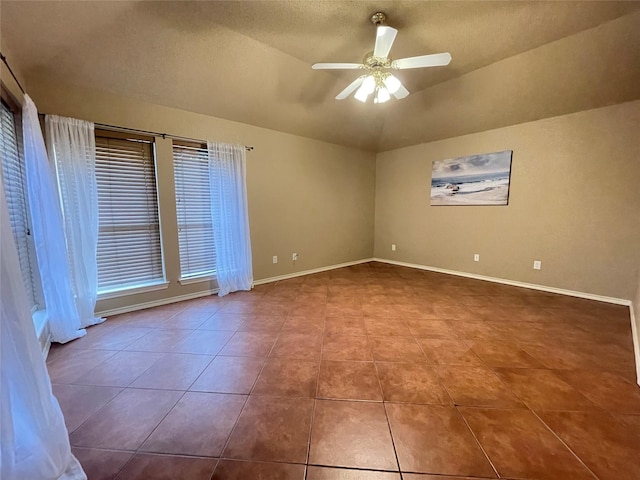 tiled empty room featuring ceiling fan, lofted ceiling, and a textured ceiling