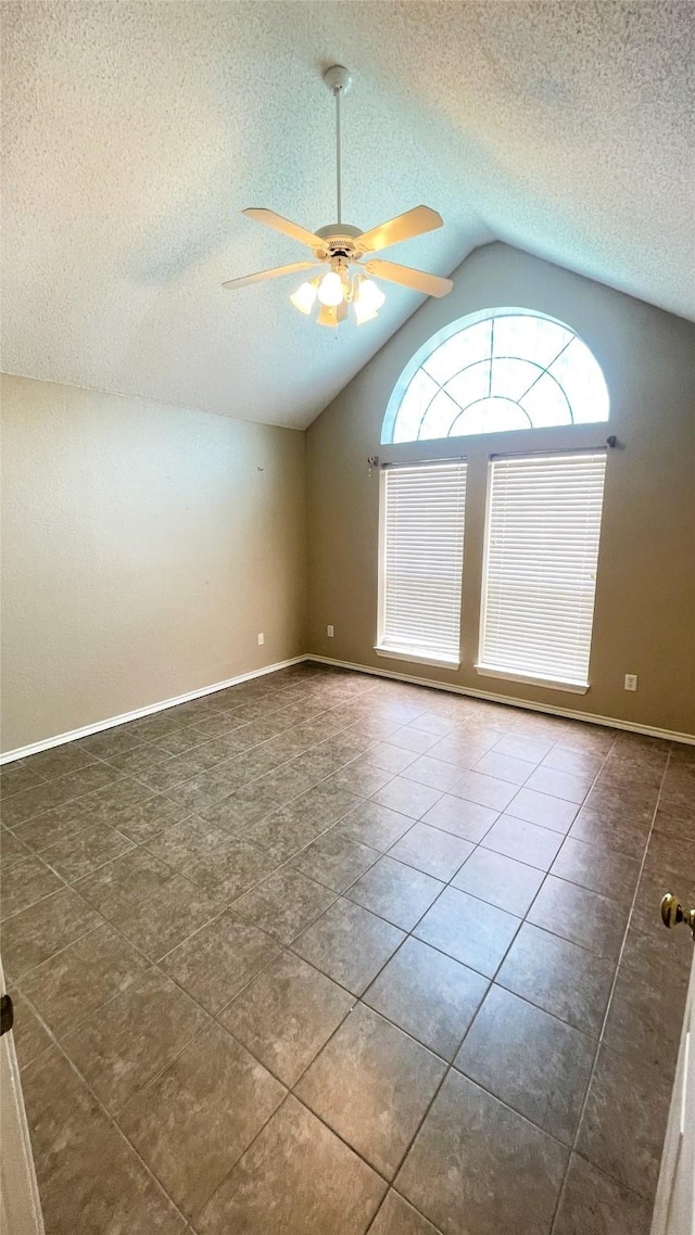 unfurnished room featuring ceiling fan, dark tile patterned floors, a textured ceiling, and vaulted ceiling