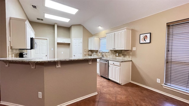 kitchen with appliances with stainless steel finishes, backsplash, a breakfast bar area, white cabinetry, and lofted ceiling