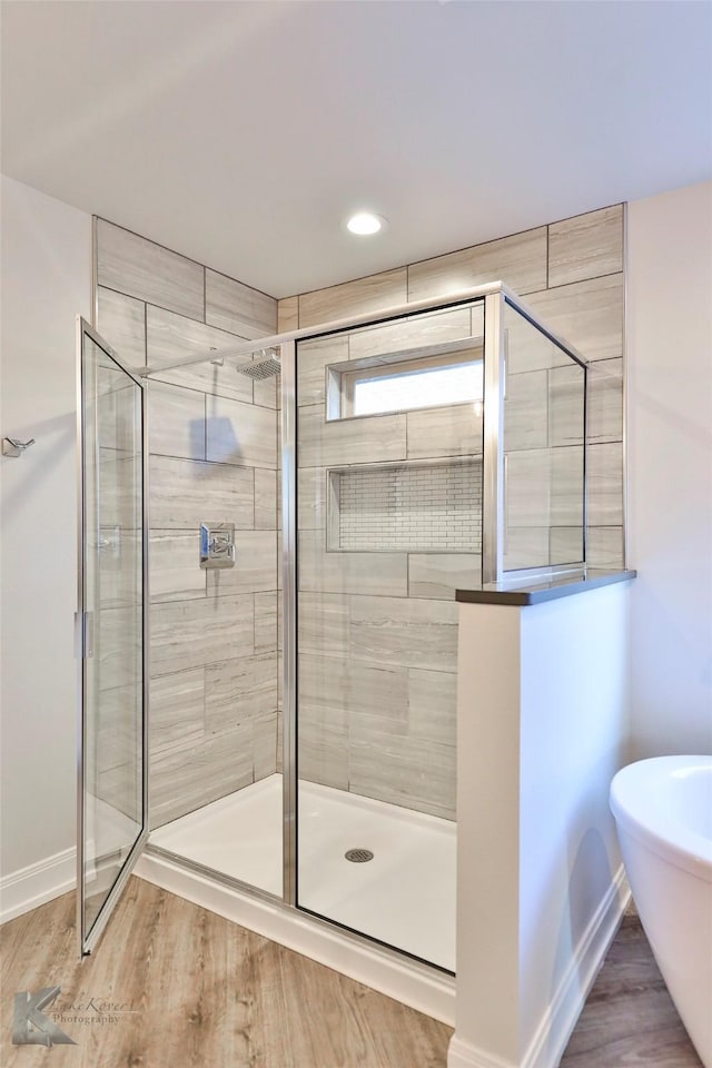 bathroom with hardwood / wood-style flooring and shower with separate bathtub