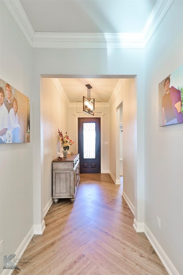 foyer entrance featuring light wood-type flooring, an inviting chandelier, and crown molding