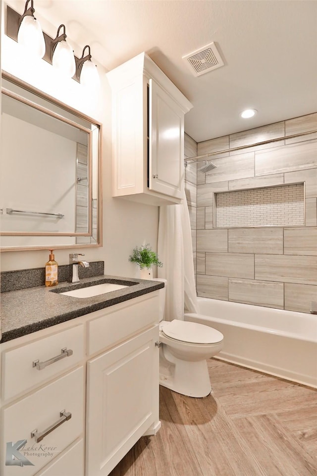 full bathroom featuring hardwood / wood-style flooring, shower / bath combo with shower curtain, vanity, and toilet