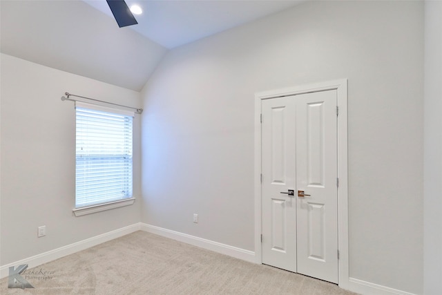 carpeted empty room featuring lofted ceiling